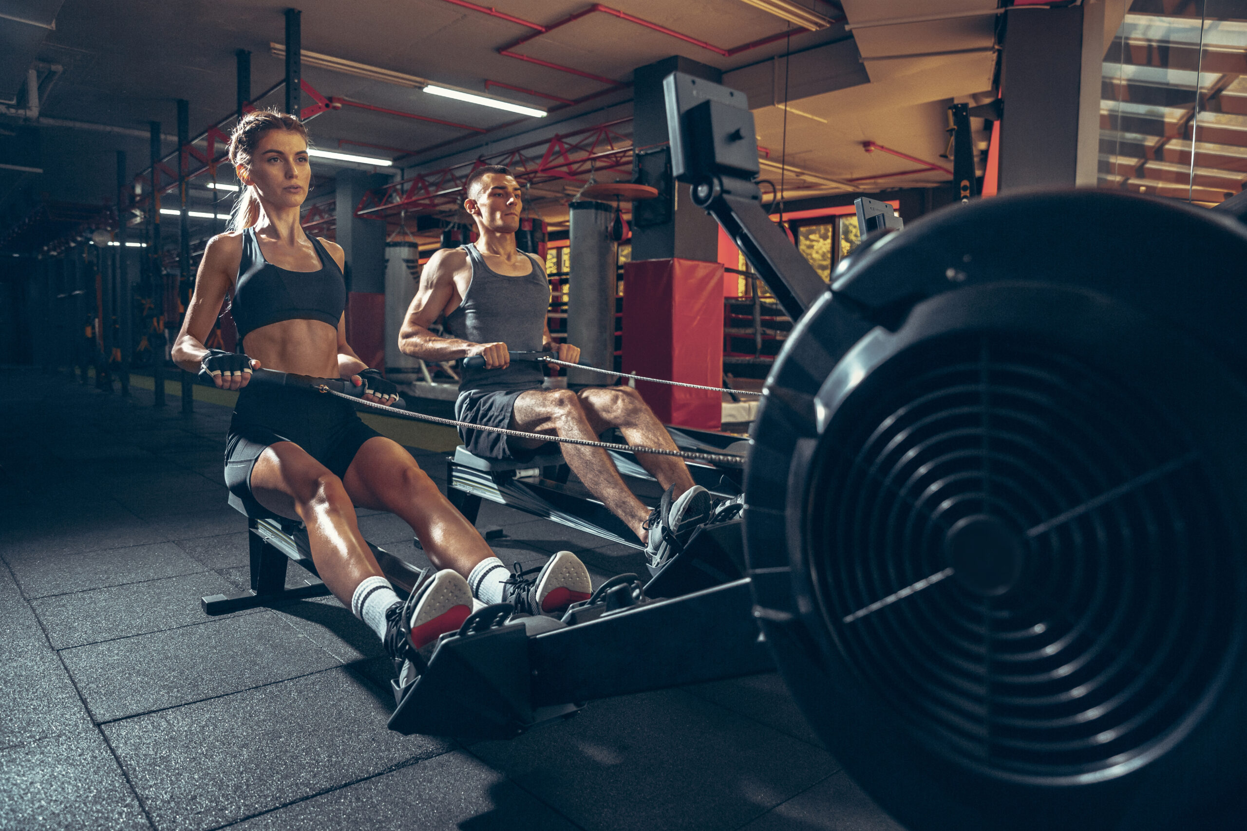 Beautiful young sporty couple workout in gym together. Caucasian man training with female trainer. Concept of sport, activity, healthy lifestyle, strength and power. Working out with weights.